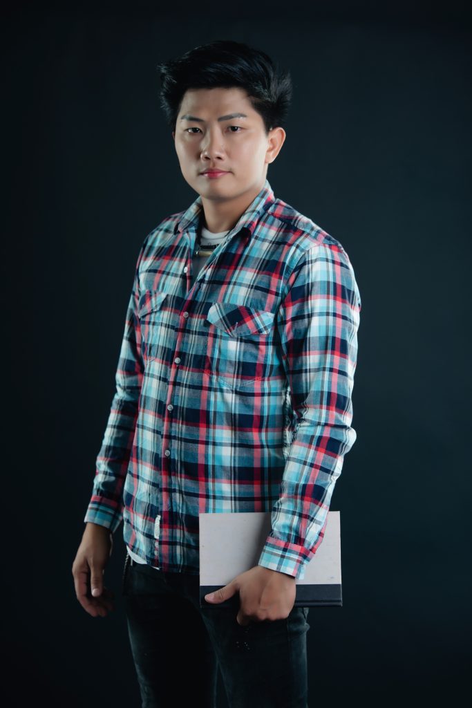 portrait of smiling young college student with books gray backgr